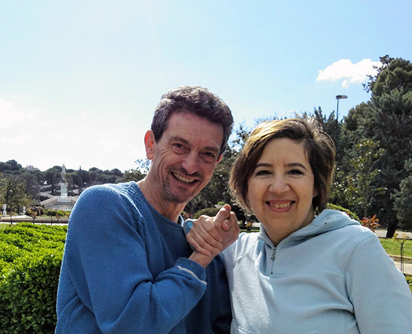foto de la parte alta del cuerpo de Ivana y de Jose Javier cogiéndose la mano entgre sus rostros sonrientes. Con la naturaleza de un parque y el 
cielo azul como fondo.
